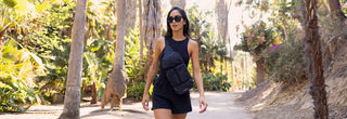 Woman walking through wooded path wearing sling bag